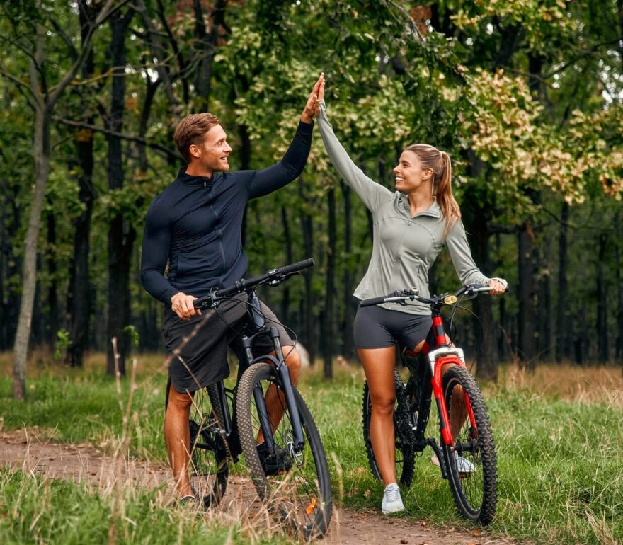 Coppia felice in bici nei boschi