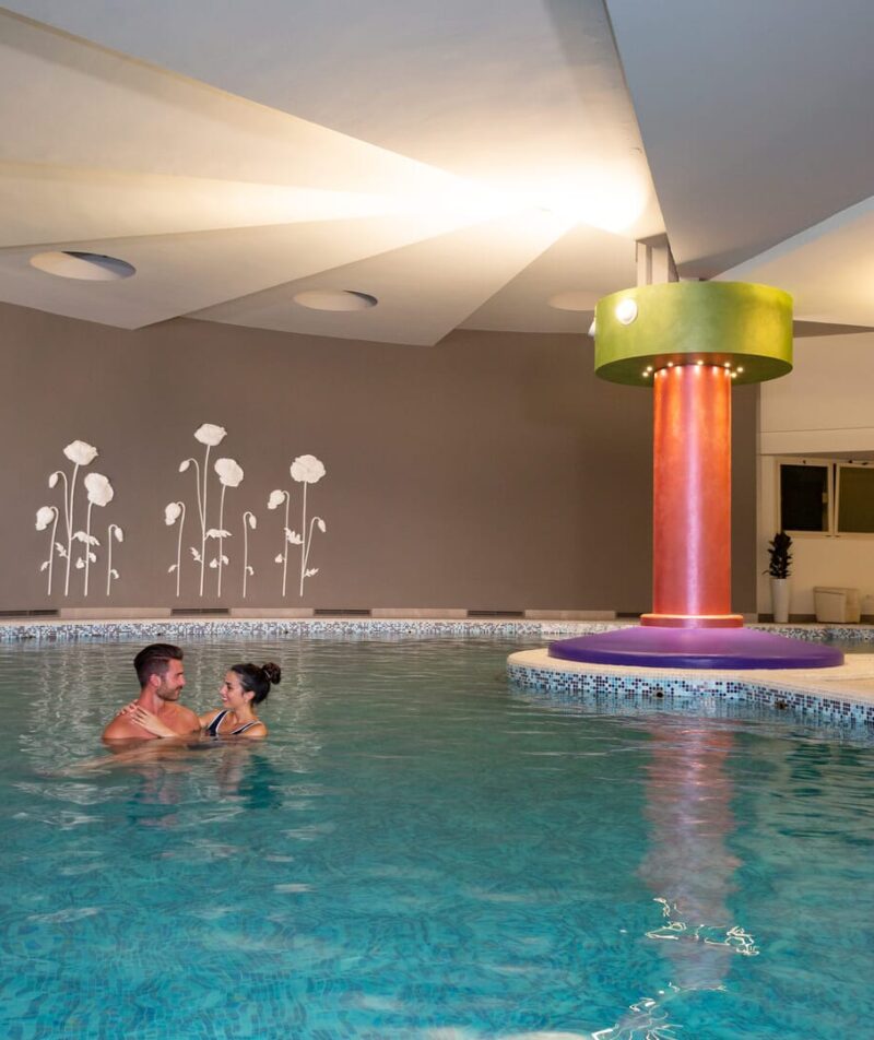 Piscina termale interna con coppia felice.